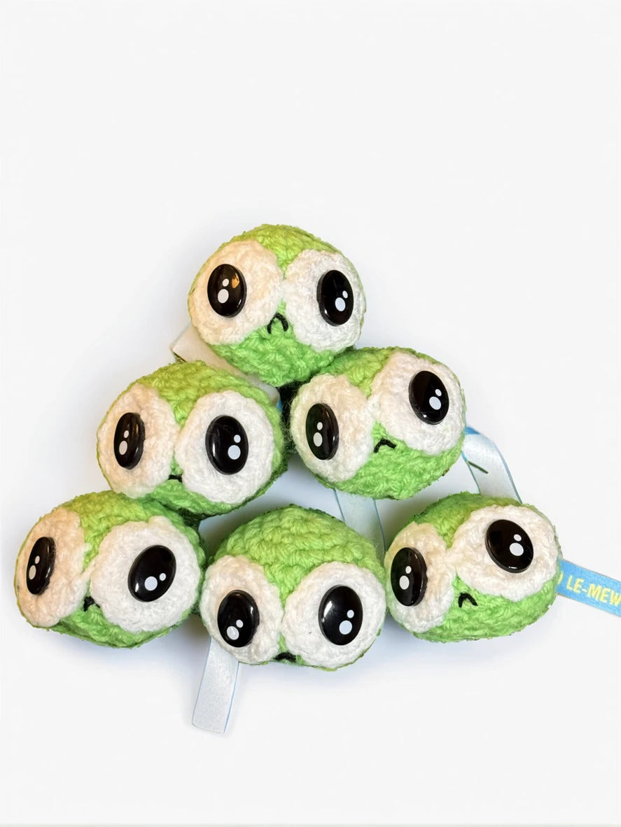 Stack of green plush cat toys with black eyes on a white background